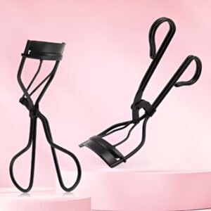 Hola Yiwu- Dos rizadores de pestañas - AGE-252 en color negro, uno vertical y otro horizontal, se muestran sobre una superficie rosa sobre un fondo rosa.